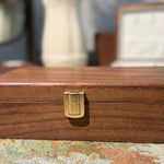 Wooden jewelry box with a gold clasp on a floral-patterned surface