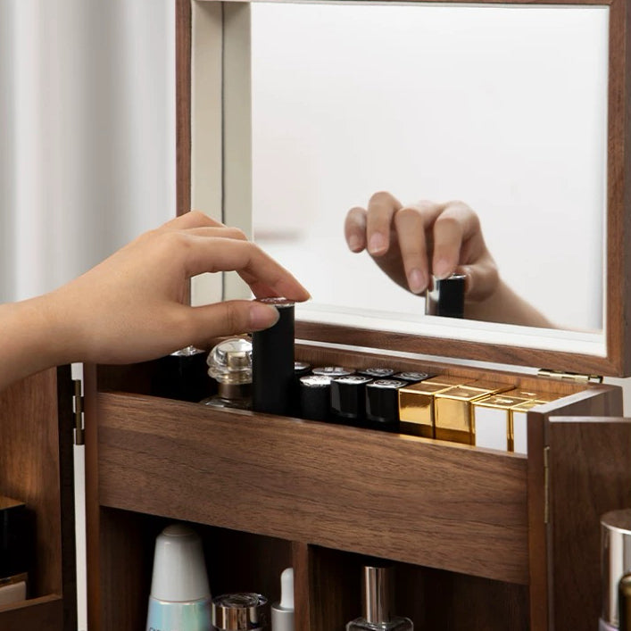 Wooden vanity with makeup products and a hand reaching for a bottle.