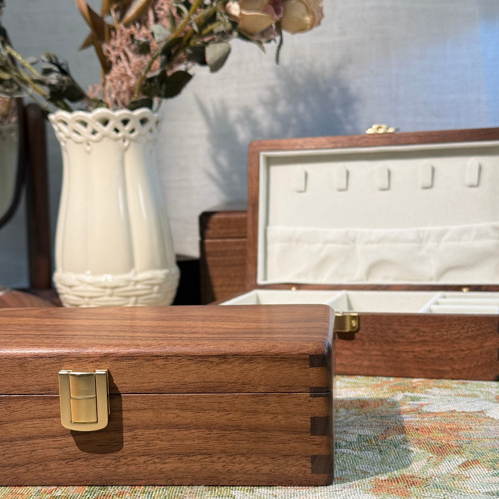 Wooden jewelry box with a gold clasp on a floral-patterned surface