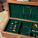 Open jewelry box with green interior displaying various jewelry items.